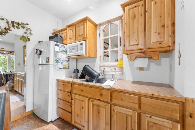 kitchen featuring light brown cabinetry, white appliances, and sink