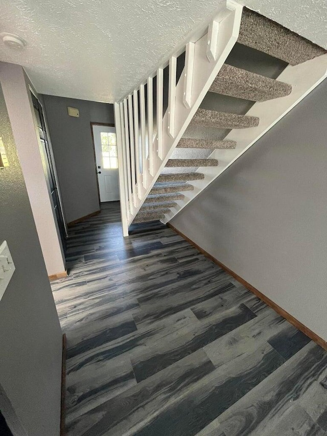 stairway with hardwood / wood-style floors and a textured ceiling