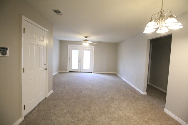 spare room with ceiling fan with notable chandelier, french doors, and carpet