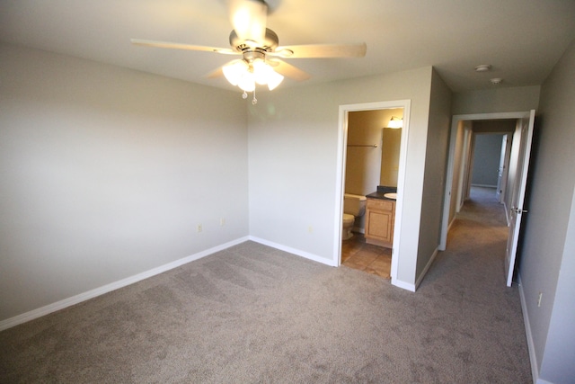 unfurnished bedroom featuring ceiling fan, dark carpet, and connected bathroom