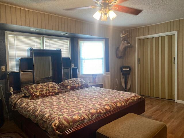 bedroom with ceiling fan, a textured ceiling, and hardwood / wood-style floors