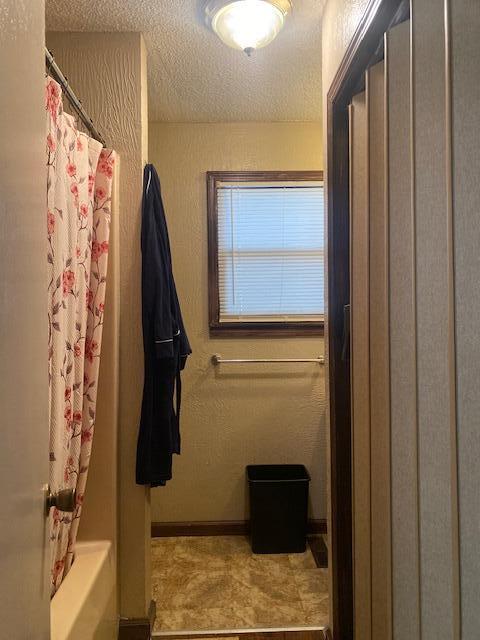 bathroom featuring shower / bathtub combination with curtain and a textured ceiling