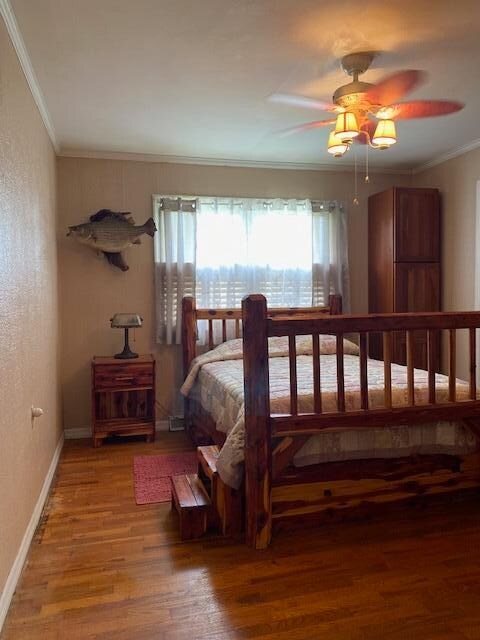 bedroom with hardwood / wood-style flooring, crown molding, and ceiling fan