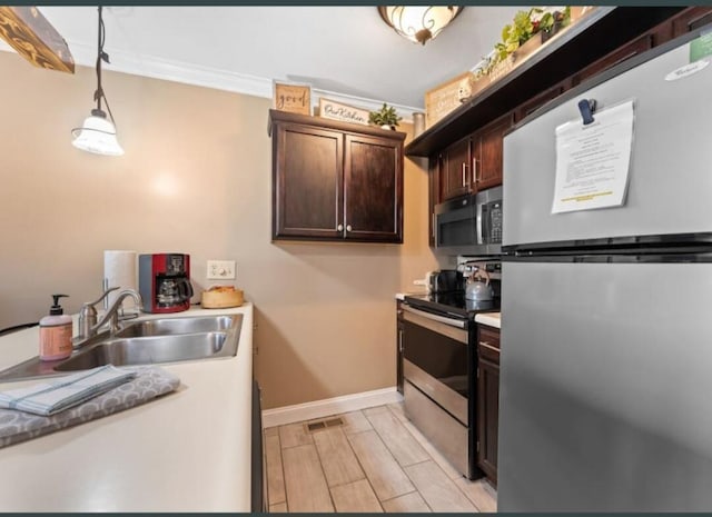 kitchen with dark brown cabinets, a sink, appliances with stainless steel finishes, baseboards, and ornamental molding