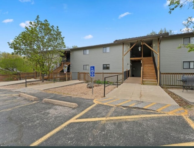 view of front of house featuring stairway, uncovered parking, and fence