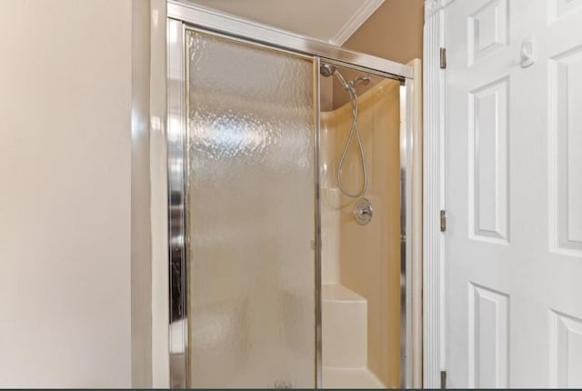 bathroom with a shower stall and ornamental molding