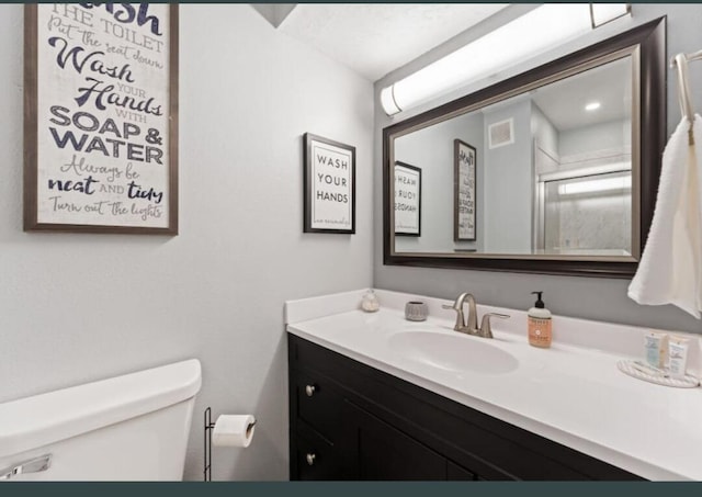 bathroom with vanity, a shower with shower door, and toilet