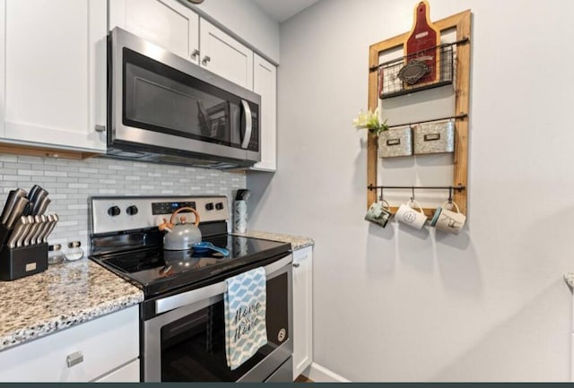 kitchen with backsplash, light stone countertops, appliances with stainless steel finishes, and white cabinetry
