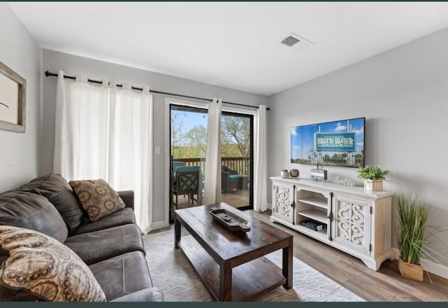 living room with wood finished floors, visible vents, and baseboards