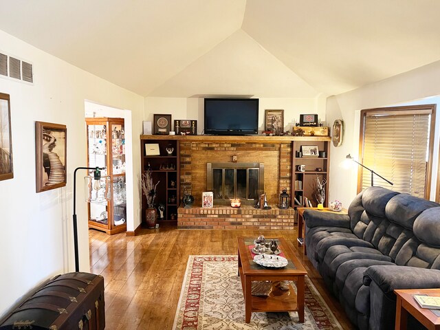 living room featuring lofted ceiling, a brick fireplace, and hardwood / wood-style floors