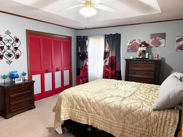 bedroom with a closet, ceiling fan, a textured ceiling, light carpet, and crown molding