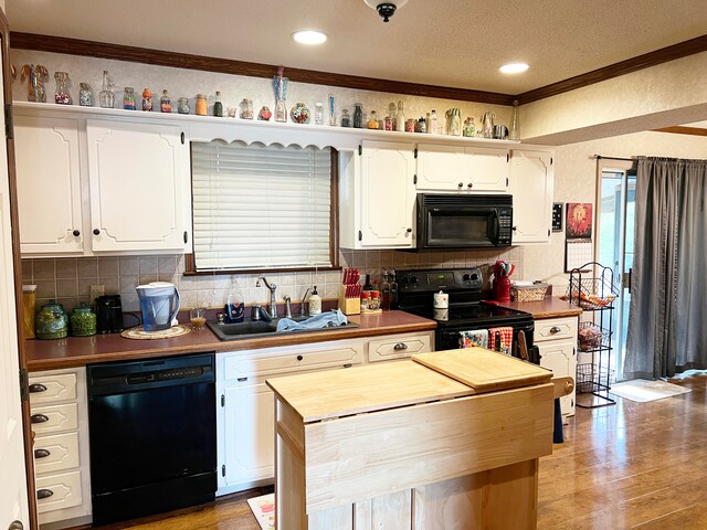 kitchen with light hardwood / wood-style flooring, sink, backsplash, white cabinetry, and black appliances