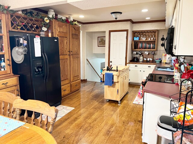 kitchen featuring sink, backsplash, light hardwood / wood-style floors, crown molding, and black appliances