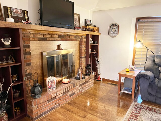 living room with a brick fireplace and hardwood / wood-style floors