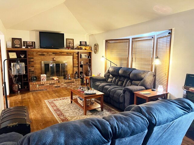 living room featuring hardwood / wood-style flooring, vaulted ceiling, and a fireplace