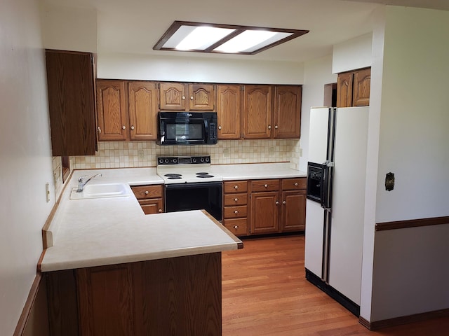 kitchen with white appliances, sink, light wood-type flooring, tasteful backsplash, and kitchen peninsula