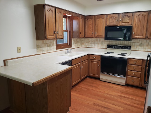 kitchen with decorative backsplash, kitchen peninsula, white electric range oven, sink, and light hardwood / wood-style flooring