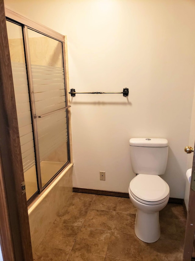 bathroom with toilet and shower / bath combination with glass door