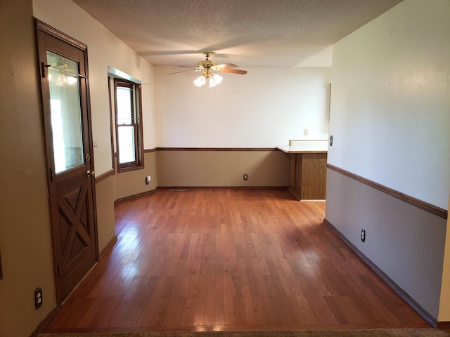 empty room featuring ceiling fan, light hardwood / wood-style flooring, and a textured ceiling