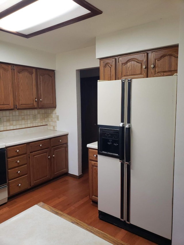 kitchen featuring decorative backsplash, stove, dark hardwood / wood-style floors, and white refrigerator with ice dispenser