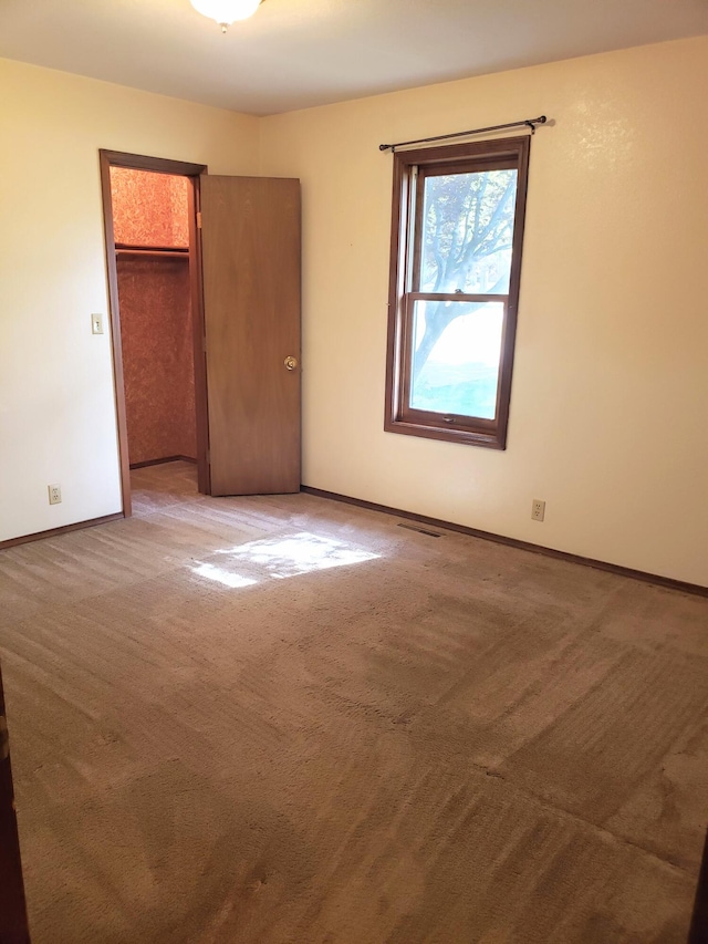 unfurnished bedroom with carpet flooring, a spacious closet, and a closet