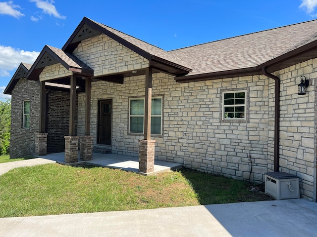 view of front of house featuring a shingled roof and a front lawn