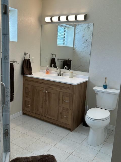 bathroom with an enclosed shower, tile patterned floors, toilet, and vanity