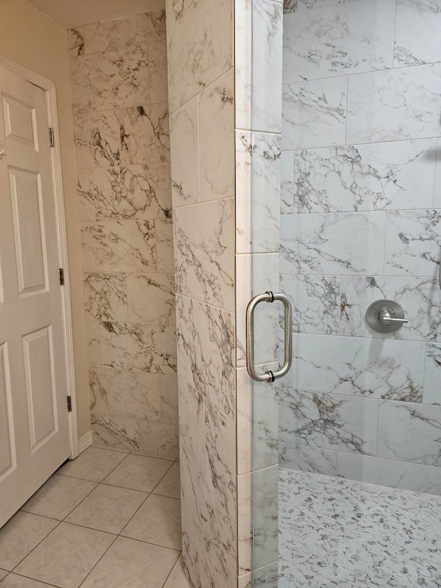 bathroom with a shower with door and tile patterned floors