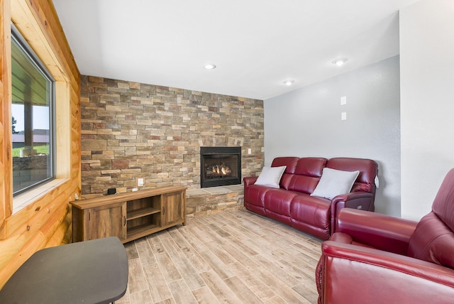 living room featuring a stone fireplace and light wood-type flooring