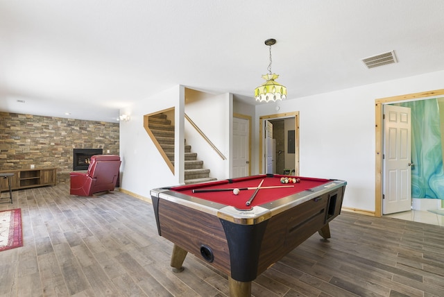 playroom with wood-type flooring, a stone fireplace, and billiards