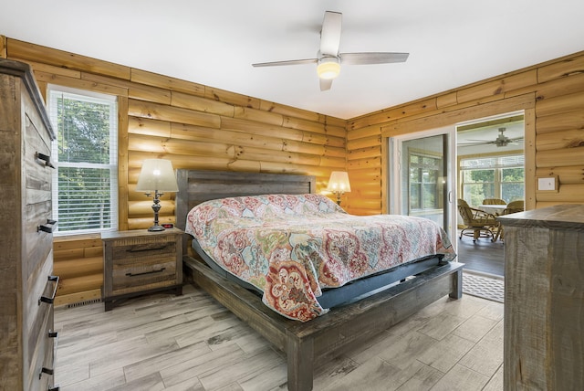 bedroom with light hardwood / wood-style floors, multiple windows, ceiling fan, and rustic walls