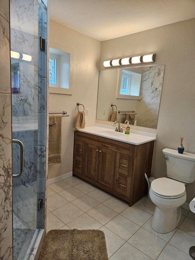 bathroom with plenty of natural light, tile patterned floors, a shower with shower door, and vanity