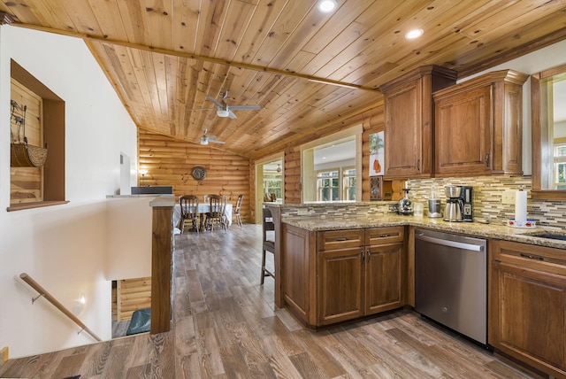 kitchen with lofted ceiling, wooden walls, hardwood / wood-style flooring, kitchen peninsula, and dishwasher