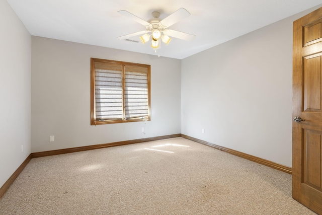 carpeted empty room with baseboards, a ceiling fan, and visible vents