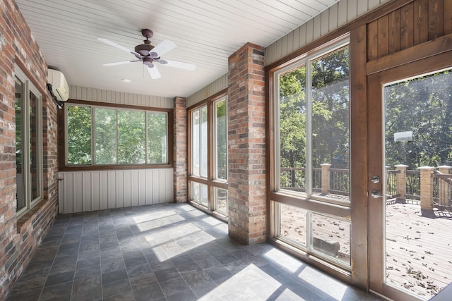 unfurnished sunroom featuring a wall unit AC, a wealth of natural light, and ceiling fan