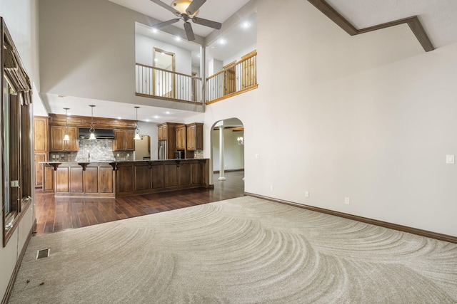 unfurnished living room featuring visible vents, a ceiling fan, arched walkways, dark wood-type flooring, and baseboards