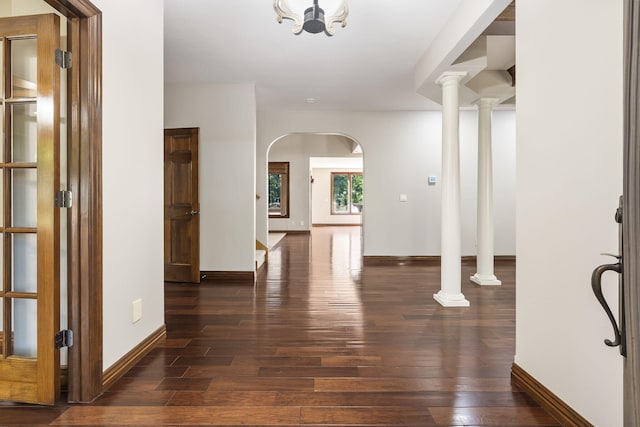 foyer entrance featuring arched walkways, baseboards, and dark wood-style floors