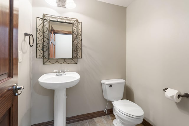 half bath with toilet, a sink, and baseboards