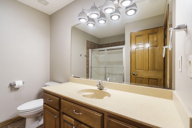 bathroom featuring a shower with door, vanity, and toilet