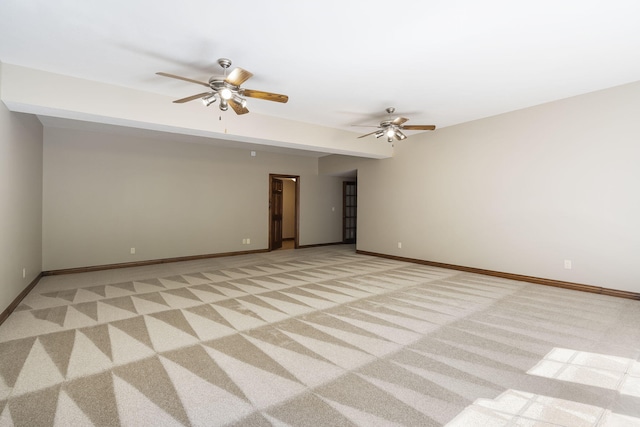 spare room featuring light colored carpet, ceiling fan, and baseboards