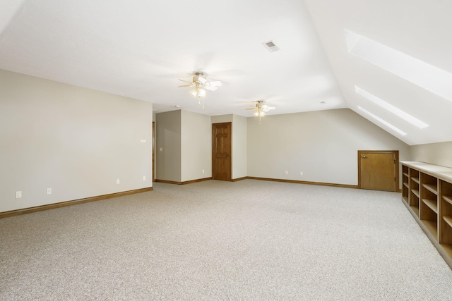 additional living space featuring ceiling fan, light colored carpet, and vaulted ceiling with skylight