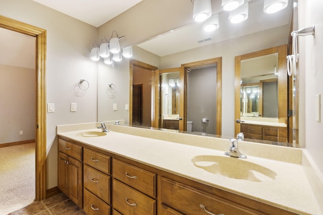 bathroom with visible vents, a sink, double vanity, and toilet