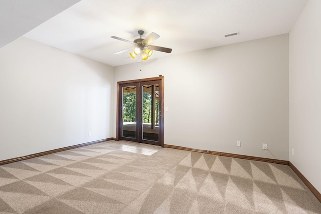 spare room with light colored carpet, baseboards, a ceiling fan, and visible vents