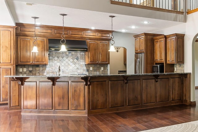 kitchen featuring custom range hood, hanging light fixtures, stainless steel fridge, and dark hardwood / wood-style floors