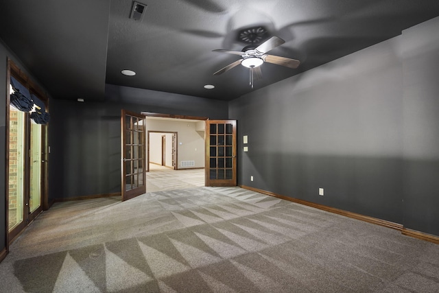 carpeted empty room with ceiling fan, plenty of natural light, french doors, and a textured ceiling