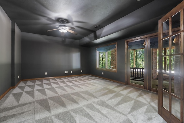 carpeted spare room featuring a textured ceiling and ceiling fan