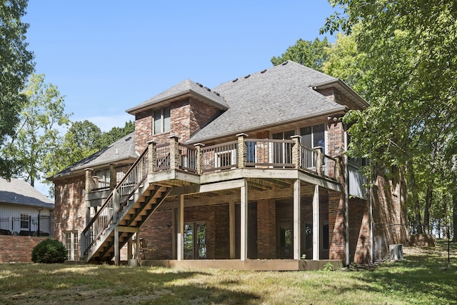 back of property with a lawn, a wooden deck, stairway, and brick siding