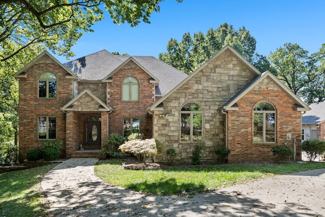 view of front of house featuring brick siding, roof with shingles, and stone siding