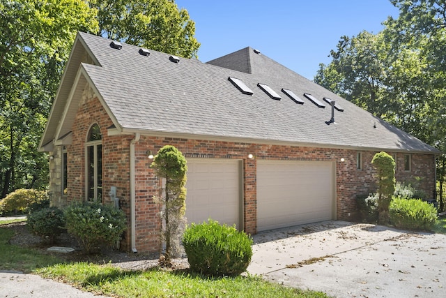 view of home's exterior with brick siding, an attached garage, a shingled roof, and concrete driveway