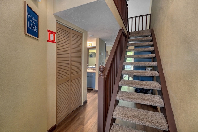 staircase featuring hardwood / wood-style flooring and a textured ceiling